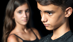 Unhappy young teen couple on a black background